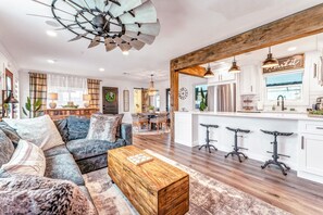 A modern living room with a sectional sofa, a wooden coffee table, and a dining area with a chandelier.