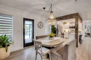 A modern kitchen with white cabinets, a wooden island, and a chandelier.
