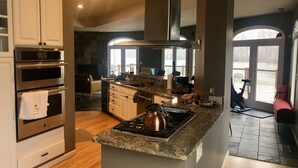 A modern kitchen with built-in appliances, a large island, and a view of a dock.