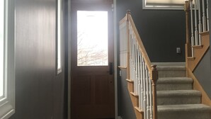 A hallway with a wooden door, a window, and a staircase.