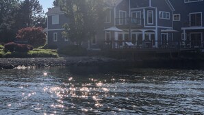 A waterfront property with a large house featuring multiple balconies and a covered patio area.