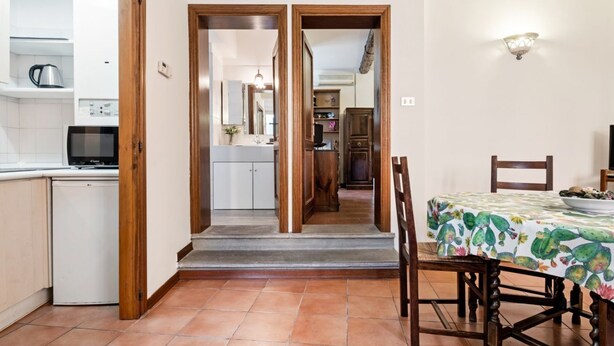 Una cucina con forno a microonde, macchina del caffè e lavastoviglie. C'è un tavolo da pranzo con sedie e una tovaglia con motivo cactus.