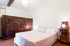 Et soveværelse med en stor seng, et træskab og et natbord med en lampe.