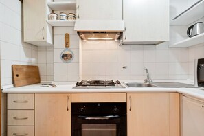A kitchen with white cabinets, a gas stove, a built-in oven, a sink, and a wooden cutting board. - GuestHost - A Central and Functional Apartment (Bologna)