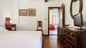 Una camera da letto con un letto, una cassettiera, uno specchio e opere d'arte alle pareti.