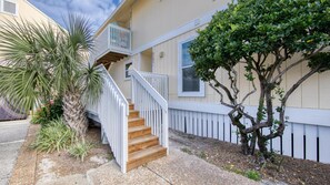 Ein zweistöckiges Haus mit einer Holztreppe, die zu einem Balkon führt.