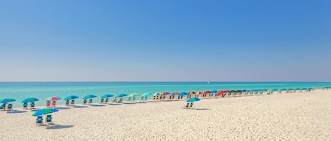 Relax on the beach with shaded seating areas and a wide, well-maintained sandy beach.