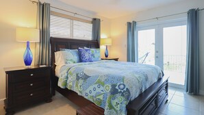 A bedroom with a bed, two bedside tables, a bench, and a view of the outside. - Paradise on the Canal with Ocean Access including Pool & Spa (Key Largo)