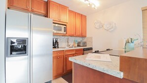 A kitchen with wooden cabinets, stainless steel appliances, a granite countertop, and decorative wall plates. - Paradise on the Canal with Ocean Access including Pool & Spa (Key Largo)