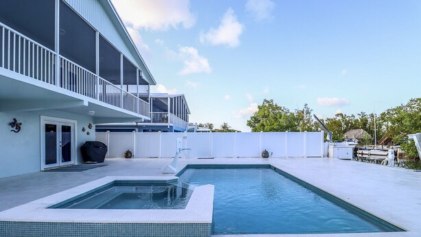 A modern house with a swimming pool, a covered patio, and a boat dock. - Paradise on the Canal with Ocean Access including Pool & Spa (Key Largo)