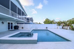 A modern house with a swimming pool, a covered patio, and a boat dock.