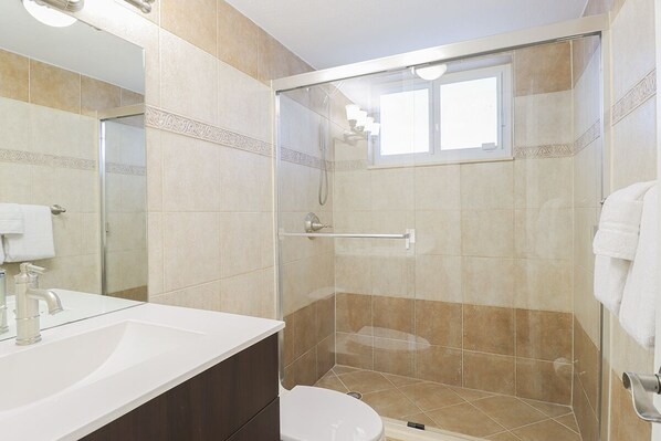 A bathroom with a shower, toilet, and sink.