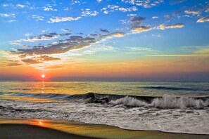 Una playa con olas y un atardecer.