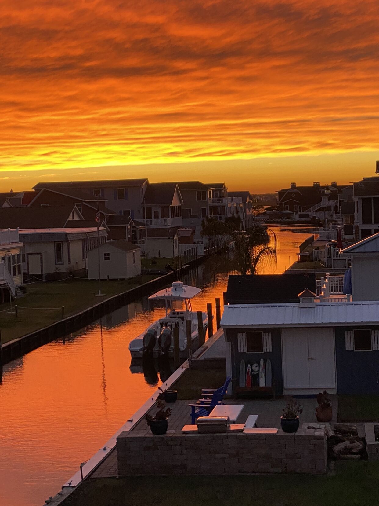 Vue sur un quartier résidentiel donnant sur le front de mer, avec des maisons, un canal et des bateaux amarrés.