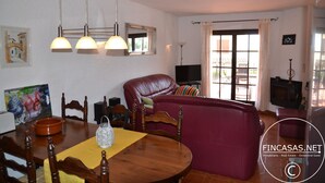Een woonkamer met een rode bank, een houten eettafel en een televisie.