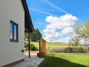 Ett modernt hus med en täckt uteplats, utsikt över landskapet och en klar himmel.
