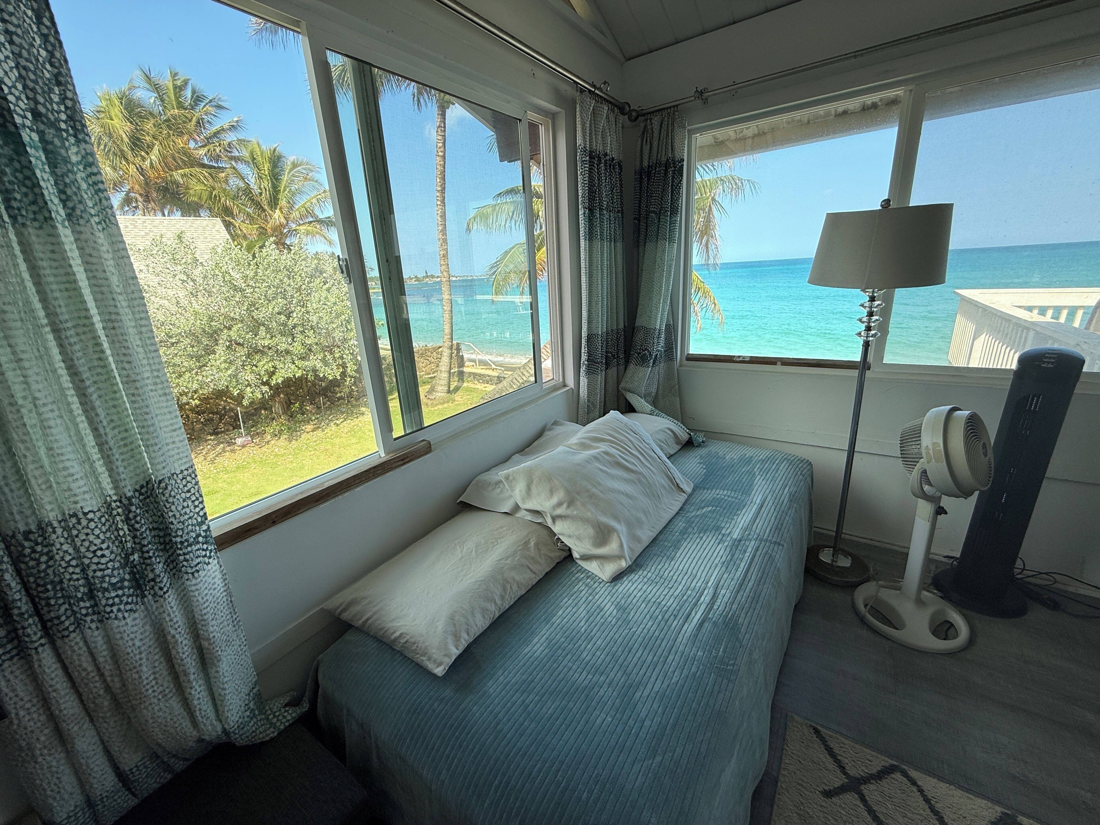 Una habitación con una cama, una lámpara y vistas al océano.