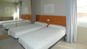 A hotel room with two single beds, a large mirror, and a window with curtains. - Rentalmar Family Acantilados (Salou)