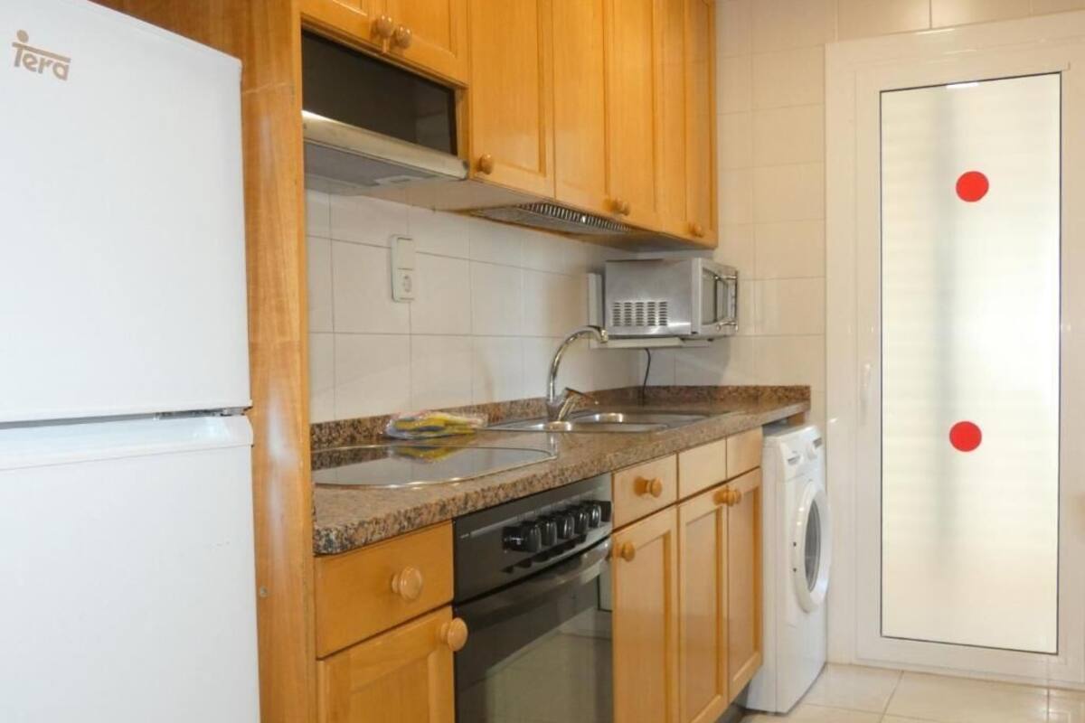 A kitchen with wooden cabinets, a built-in microwave, a dishwasher, and a washing machine.