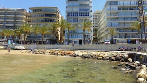 A beachfront hotel with multiple floors, palm trees, and a rocky shoreline. - Rentalmar Family Acantilados (Salou)