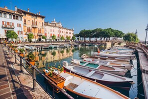 Un port de plaisance où les bateaux sont amarrés le long d’une promenade en bord de mer, entouré de bâtiments historiques et d’arbres.