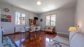 Una sala de estar con sofá, mesa de comedor, sillas y televisor.
