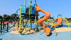 A playground with a climbing structure and slides.