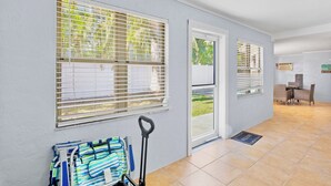 A hallway with a wheelchair, a dining area with chairs, and a door leading outside. - Family Friendly Home, 4 mins to Beach! - Starfish Cove, B (Holmes Beach)