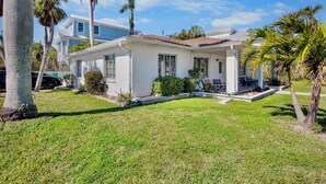 A two-story house with a white exterior, a covered porch, and a well-maintained lawn. - Family Friendly Home, 4 mins to Beach! - Starfish Cove, B (Holmes Beach)