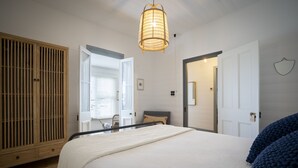 Quarto com uma cama grande, um guarda-roupa de madeira e um candeeiro pendente.