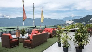 A terrace with wicker furniture and potted plants, overlooking a mountainous landscape. - The Fern Denzong Hotel & Spa Gangtok (Gangtok)