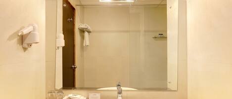 Un baño con lavamanos, espejo y perchero para toallas.