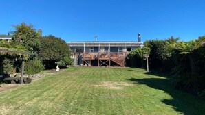 A residential building with a covered deck and a lawn in front. - Wake Up by the Lake | Private Jetty, Kayaks & Cosy Comforts (Rotorua)