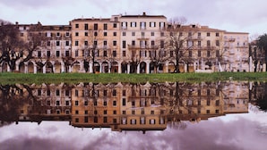 A row of multi-story buildings reflected in a calm body of water. - City walls sea view (Corfu)
