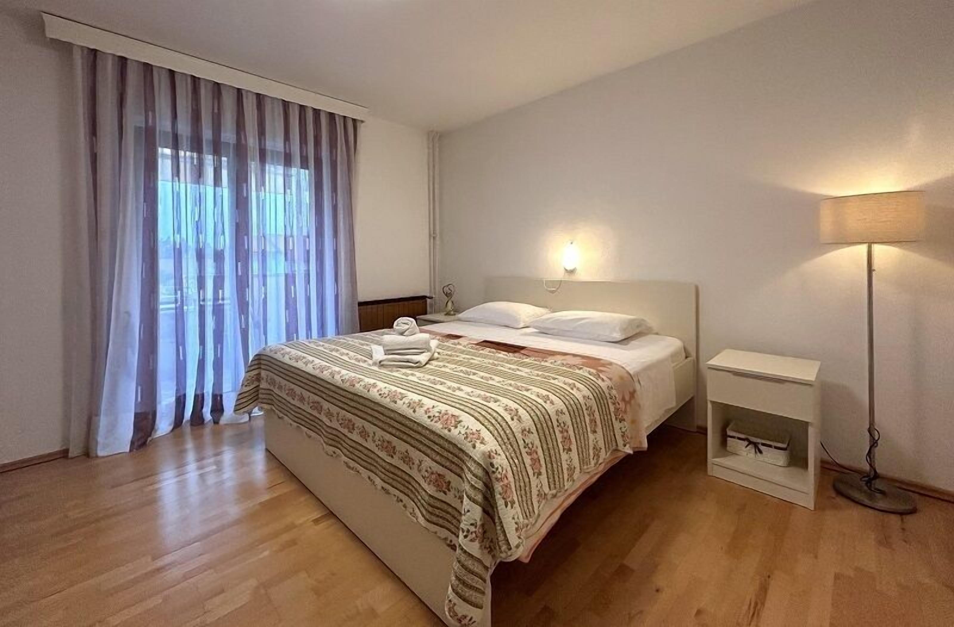 A neatly arranged bedroom with a bed, bedside tables, and a lamp.
