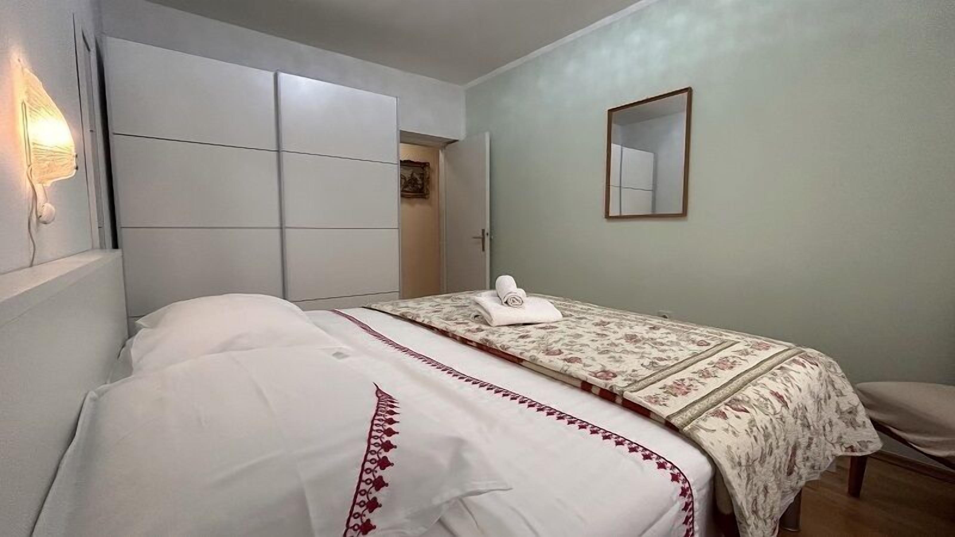 Une chambre à coucher comprenant un lit, une armoire, un miroir et une porte donnant sur une salle de bain.