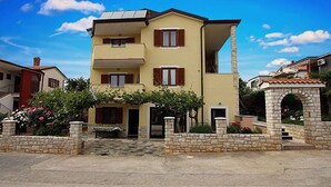 A two-story building with a balcony, stone walls, and a garden with flowers. - Apartment 823/1920 (Istria - Novigrad), 150m from the beach (Novigrad)