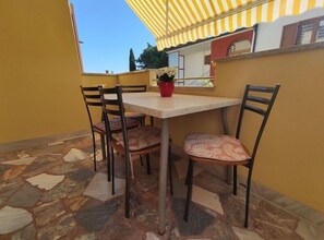 Un patio con tavolo e sedie, una pianta in vaso e un tendaggio a righe.