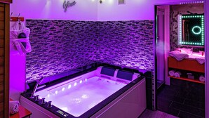 Un baño moderno con una bañera grande, un tocador con espejo y un perchero de toallas en la pared.