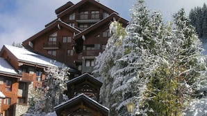 Eine Holzhütte mit Balkon, umgeben von schneebedeckten Bäumen.