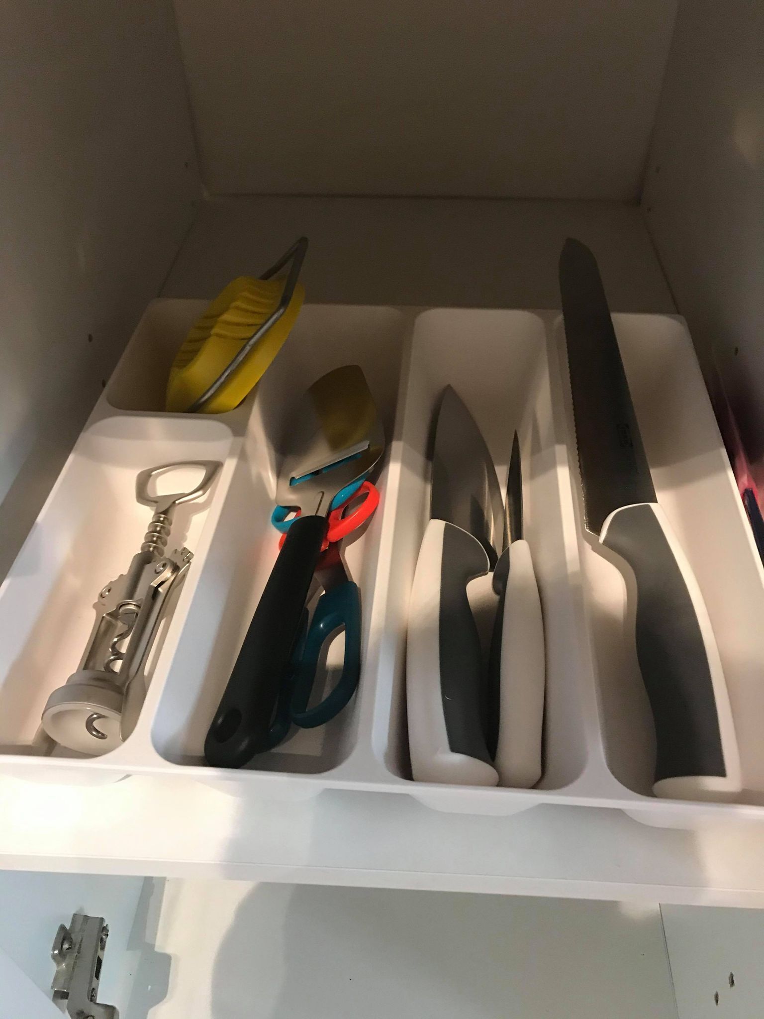 A drawer with compartments containing various tools and utensils.