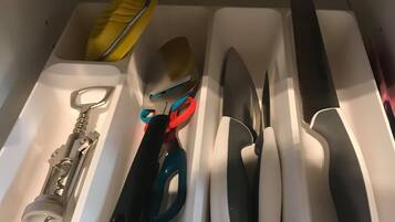 A drawer with compartments containing various tools and utensils.