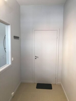 A hallway with a white door, a small window, and a black mat on the floor. - Notodden Sentrum Apartment NO 10 (Notodden)