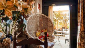 A wicker chair with a cushion, a wicker basket, and a vase with flowers.