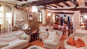A cozy room with wicker furniture, a stone wall, and a dining area with a table and chairs.