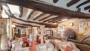 A rustic interior with exposed wooden beams, wicker furniture, and stone walls.