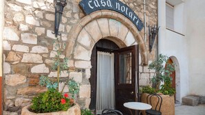 An outdoor seating area with stone walls, a door labeled "casa notari," and potted plants.