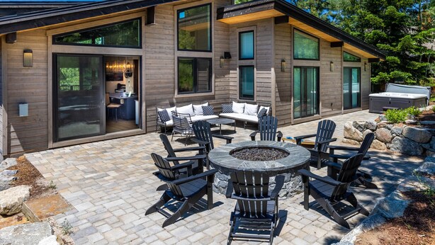 A modern house with a patio area featuring a fire pit and outdoor furniture.