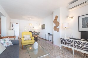 A modern living room with a sofa, armchair, coffee table, and a TV stand.