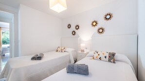 Een hotelkamer met twee bedden, een nachtkastje, een lamp en decoratieve spiegels aan de muur.